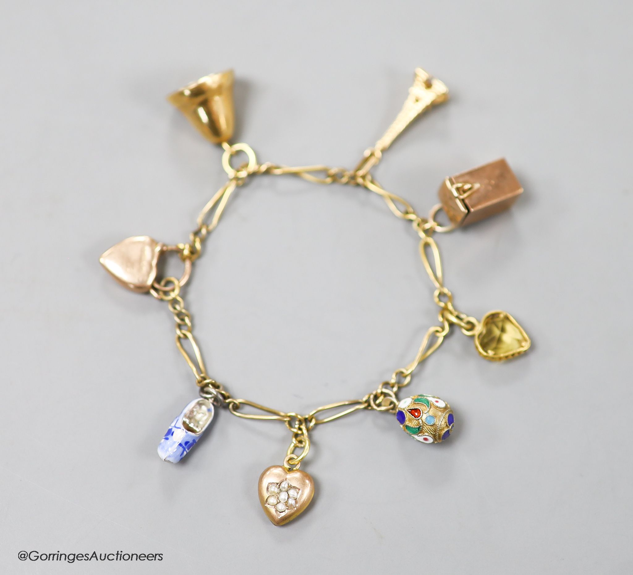 A small Edwardian 9ct gold charm bracelet, hung with eight assorted charms, approx. 16cm, gross weight 9.7 grams.